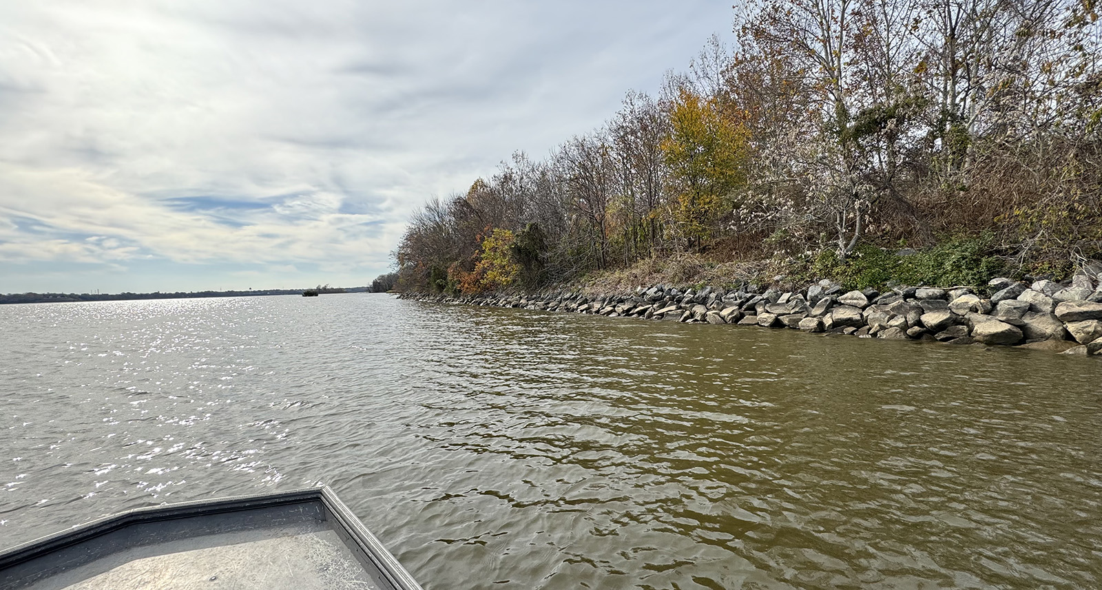 Photo prise à partir d'un petit bateau d'un rivage bordé de gros blocs de roche, appelés enrochements.