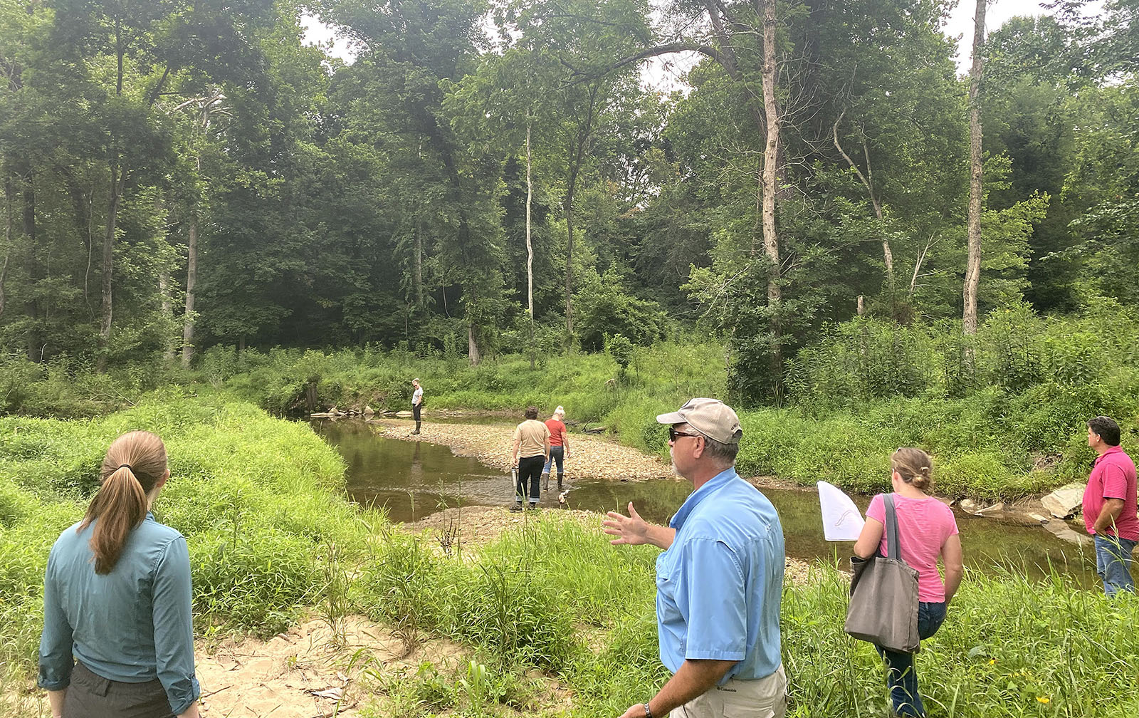 Un groupe de personnes se réunit sur les rives d'un cours d'eau, en pleine discussion.