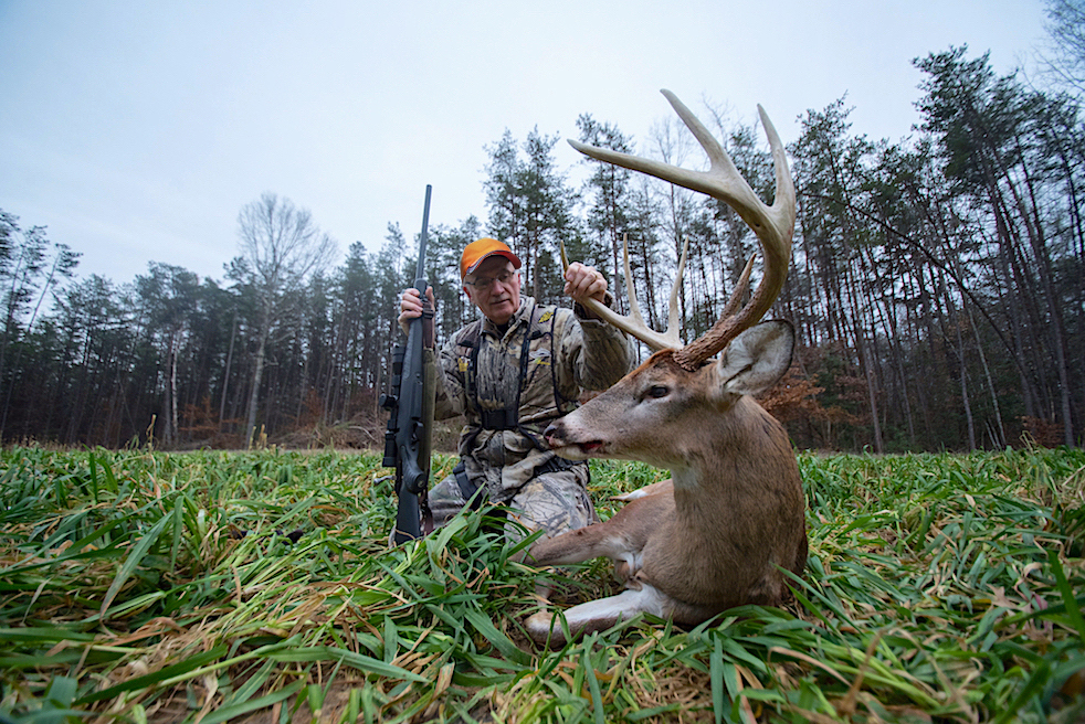 Image d'un homme avec un cerf mort qu'il a tué avec un fusil.