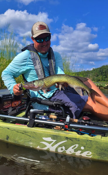 Un homme dans un kayak de pêche assis tenant un doré vert.