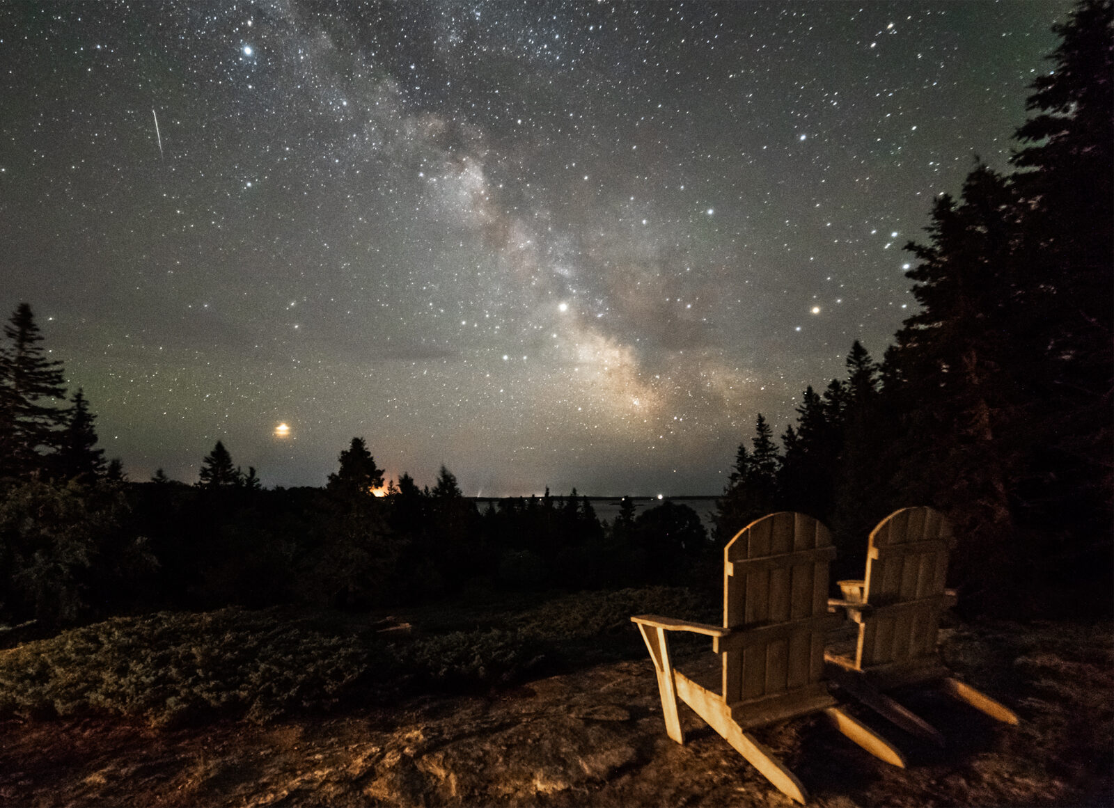 Image de deux chaises regardant la galaxie tourbillonnante d'étoiles dans le ciel nocturne.
