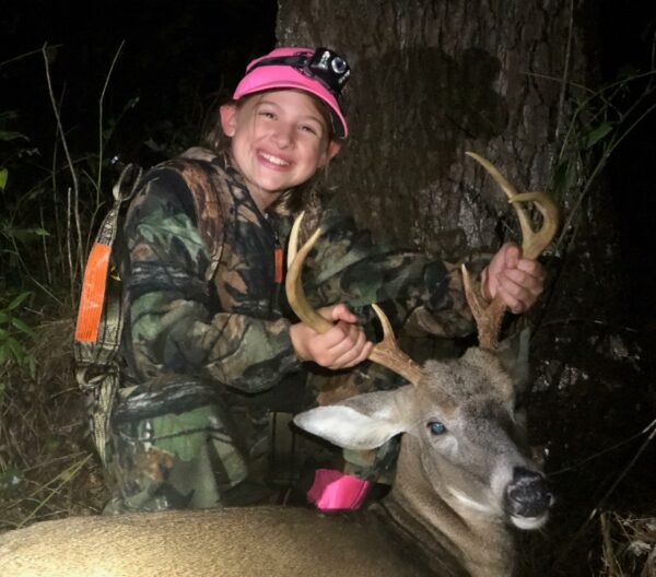 Image d'une jeune fille avec le cerf mâle qu'elle a tué.