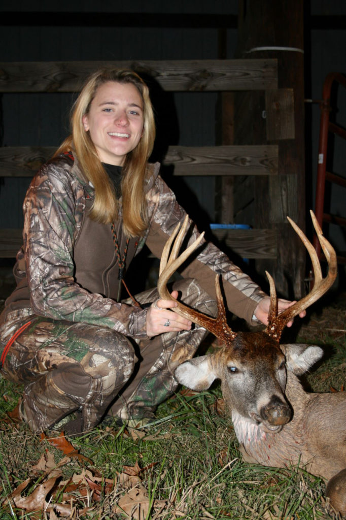 Image d'une femme posant avec un cerf mort qu'elle a tué.