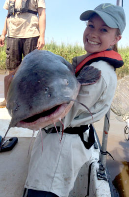 Une fille tenant un grand poisson-chat bleu